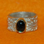 Zilveren kantring met blauwgroene tourmalijn in gouden kast